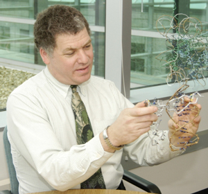 NIGMS Director Dr. Jeremy M. Berg uses wire models he constructed to show how a zinc finger protein fits into the major groove of double-helical DNA