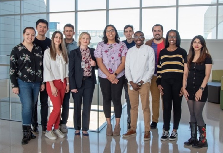 A group of students standing around Dr. Jones in a large open space