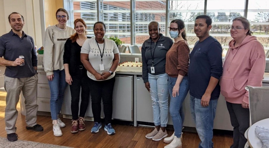 Dr. Sankoh posing with seven others, with a farewell cake on the table behind them.